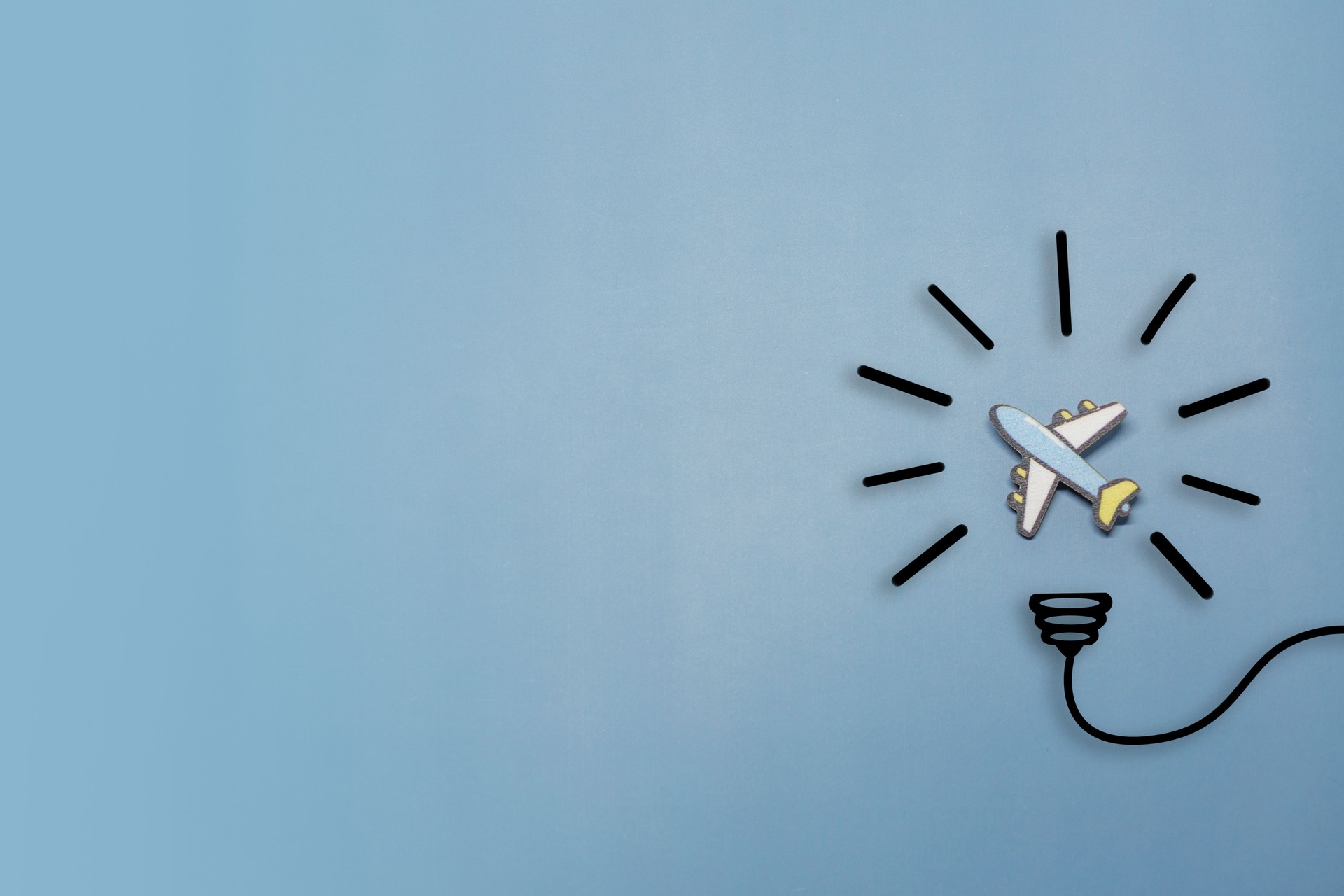 Idea symbol in the form of a painted light bulb with Toy airplane inside on a blue background. Time to travel.